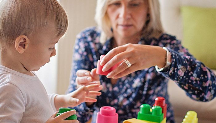 Female caregiver building legos with young child