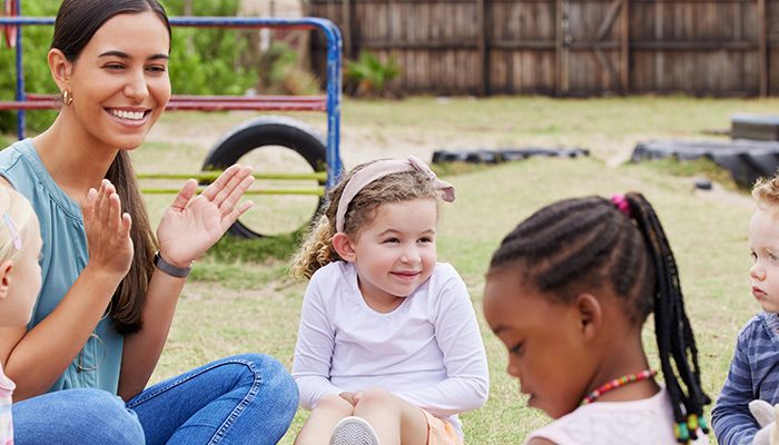 Young children and their teacher sitting in a circle outdoors