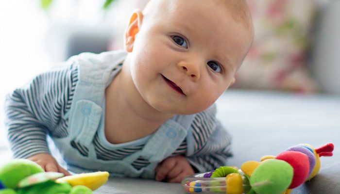 Baby laying on stomach with toys in front of them